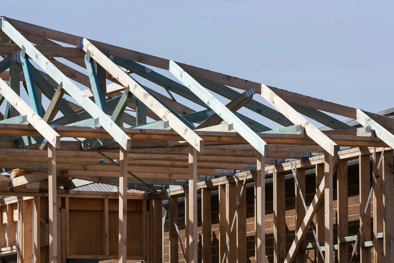 Roof trusses and wall framing on a new single-family home under construction against a clear sky