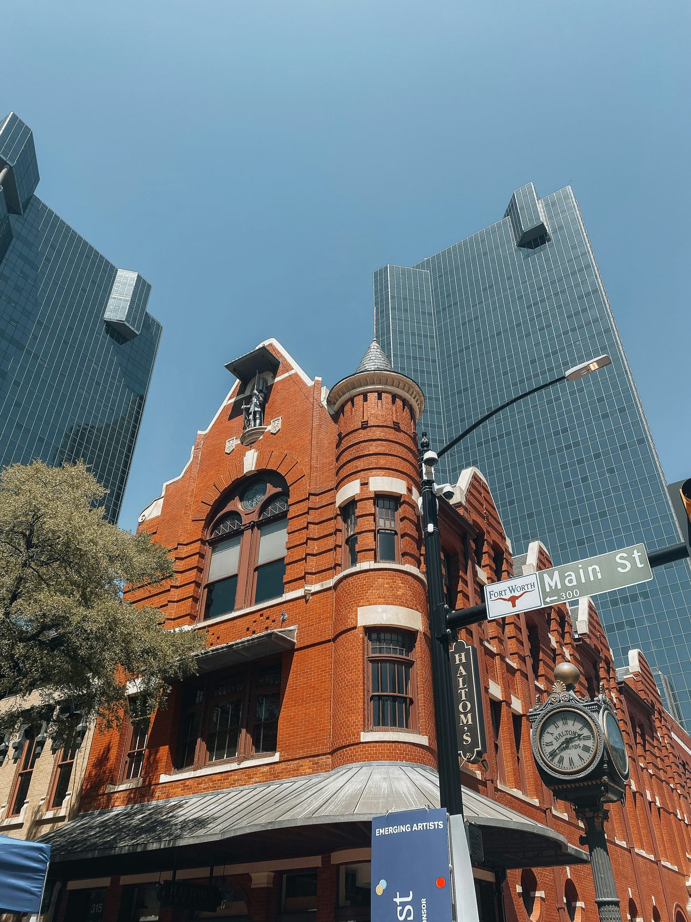 Historic red brick building at the corner of Main Street in downtown Fort Worth, Texas, framed by modern glass towers