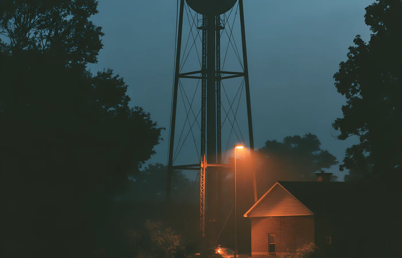 Water tower silhouette at blue hour beside a lit street lamp, north Texas